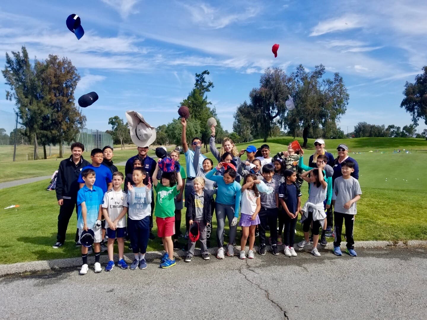 An SV Golf camp group throwing their caps in the air on the course